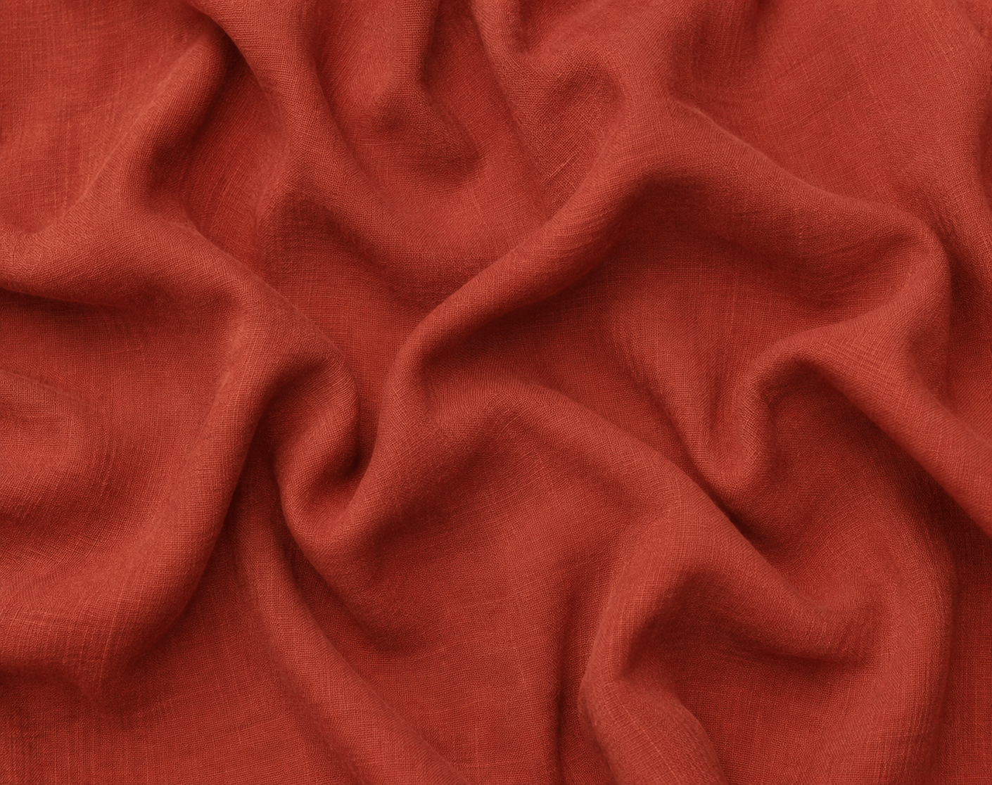 A close-up of terracotta 100% linen fabric with soft folds and a smooth, slightly lustrous texture.